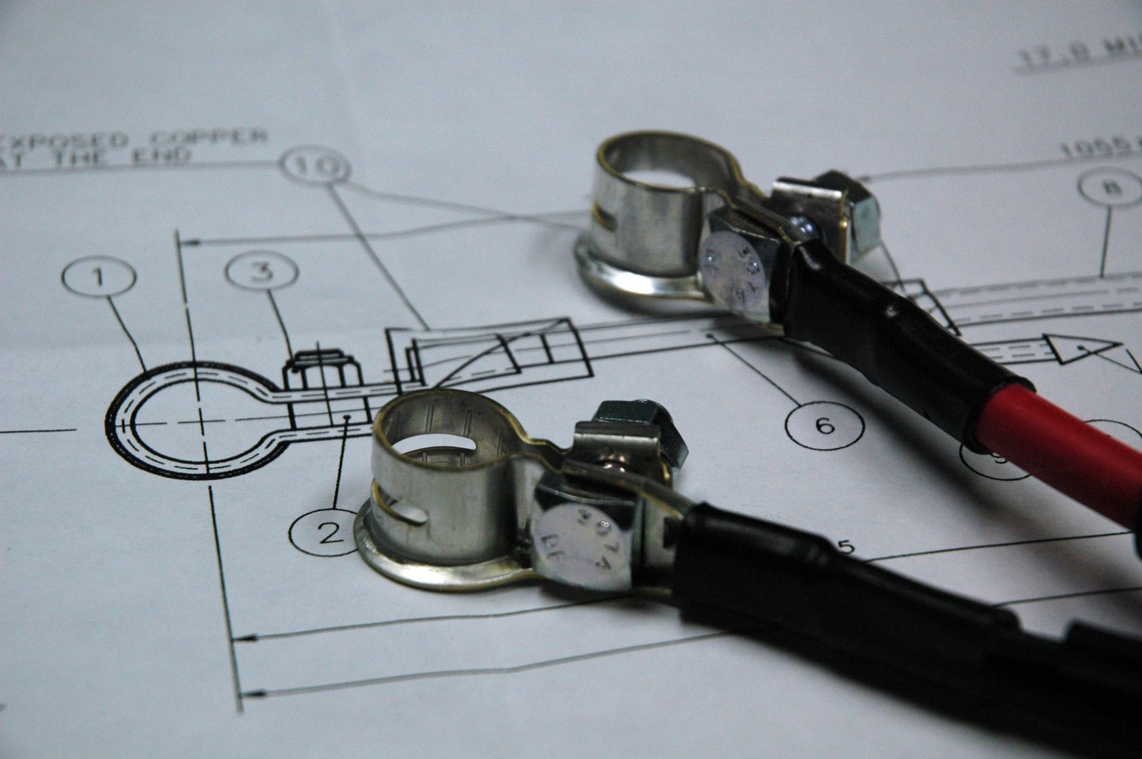 Battery cable terminals shown over an engineering drawing