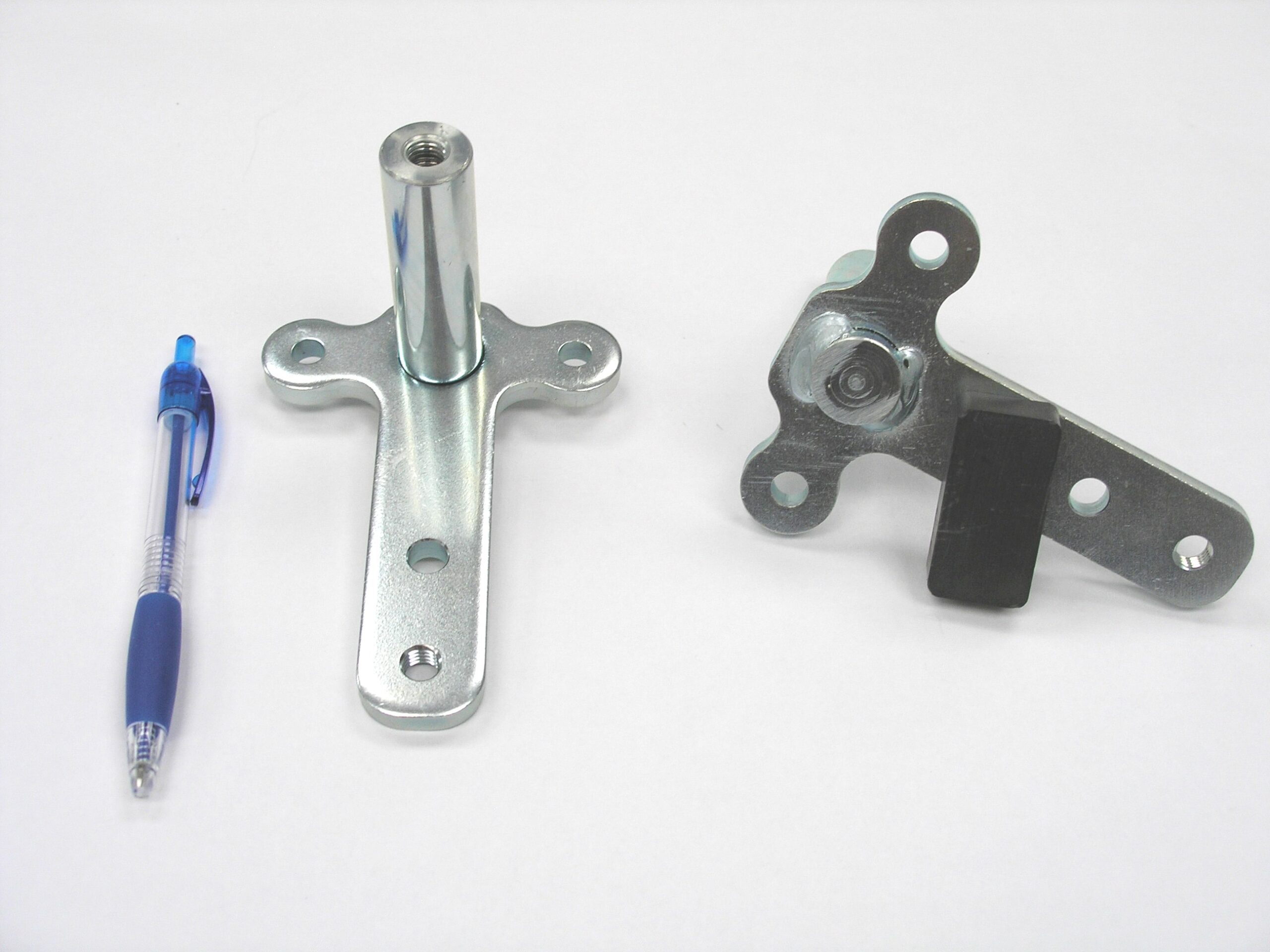 Two formed brackets, one with an upright tube, beside a pen for scale