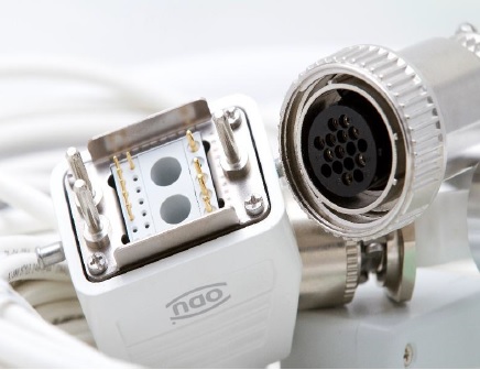 White rectangular cable plug beside a circular metal connector with pin sockets