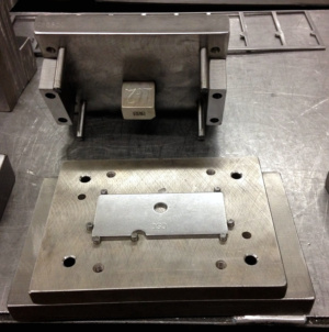 Rectangular plate with a central circular hole on a perforated tooling base